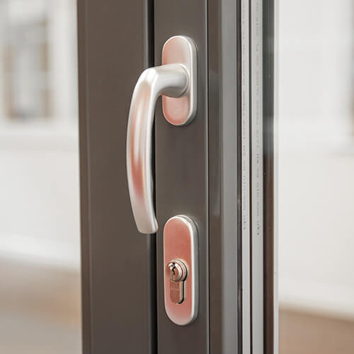 Visar handtag med nyckel på utsidan på en vikdörr i trä. Handtaget sitter på gångdörren.